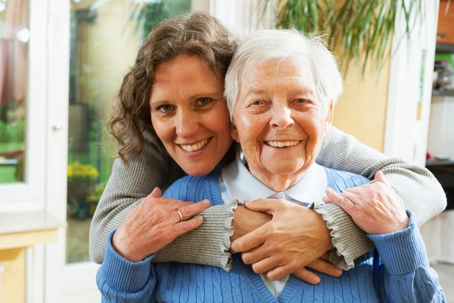 younger woman with hands around older woman smiling